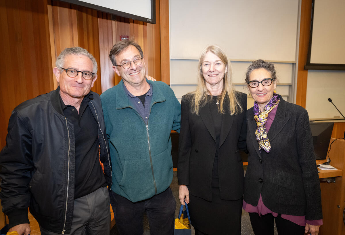 Goodman, Isacoff, Bargmann, and Shatz standing with their arms around each other in a lecture hall, smiling.